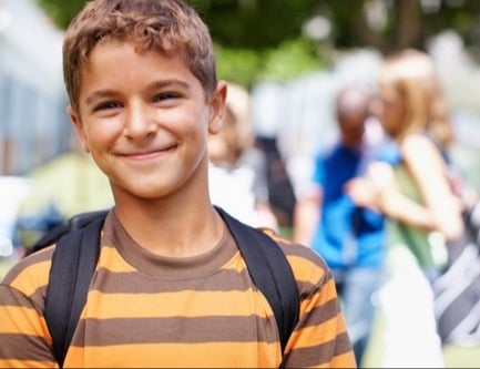 Smiling boy with backpack outside