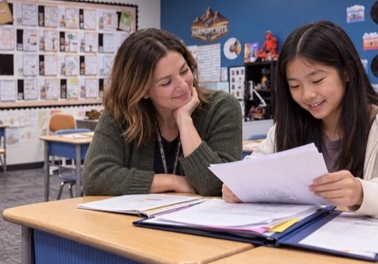Teacher and student reviewing a sheet of paper together.