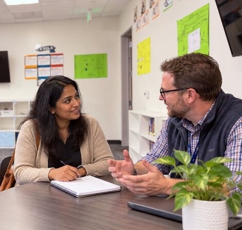 Two adults discussing paperwork at a table.