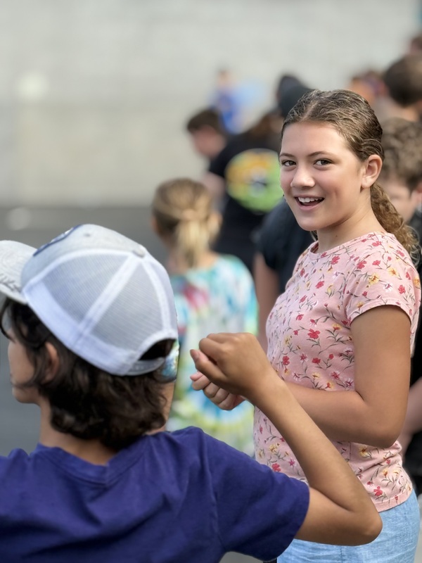 Student smiling and playing outside with other students.