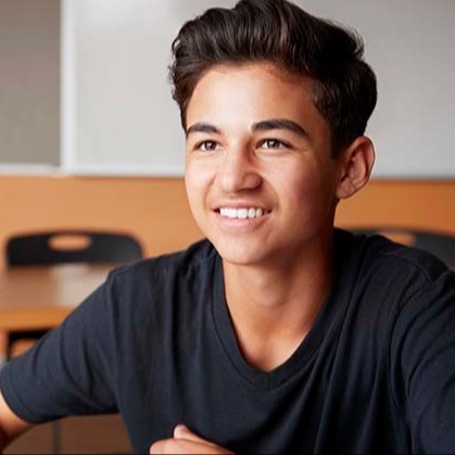 Student smiling while talking with someone across a table. Student smiling while talking with someone across a table.