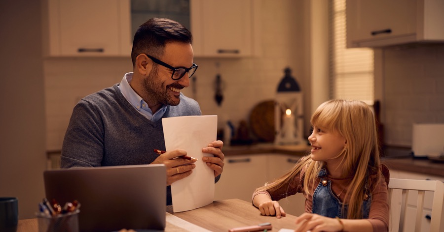 Father and daughter sitting at a table doing homework